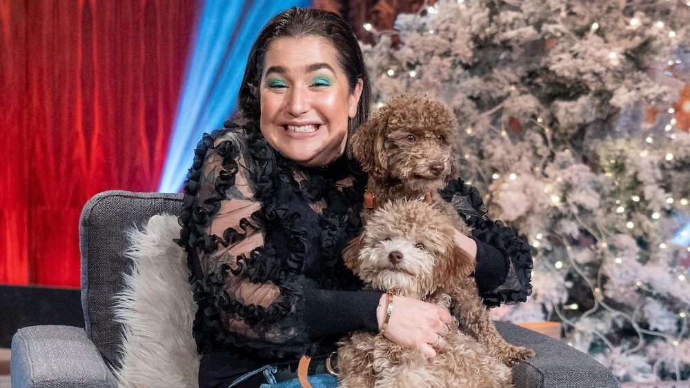 Sur le plateau des Poilus, Mariana Mazza es assise sur un fauteuil avec ses chiens et sourit.