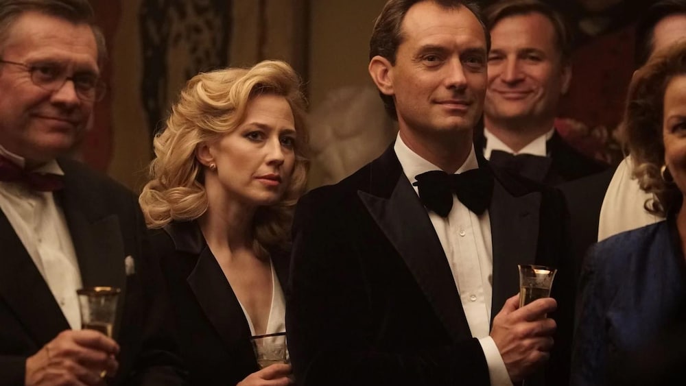 Un homme et une femme en tenues de soirée, un verre à la main.