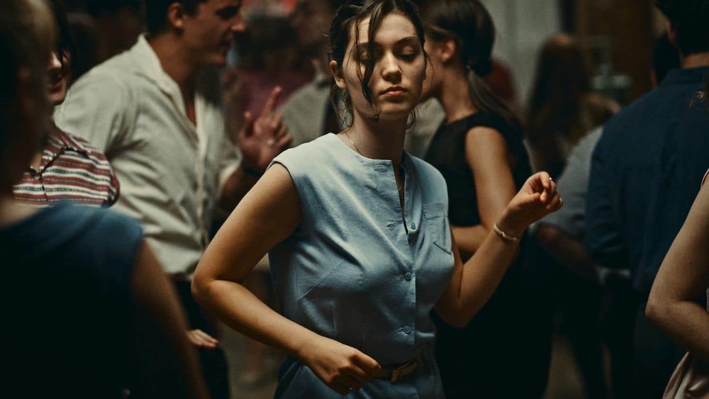 Une jeune femme danse au milieu d'autres jeunes gens.