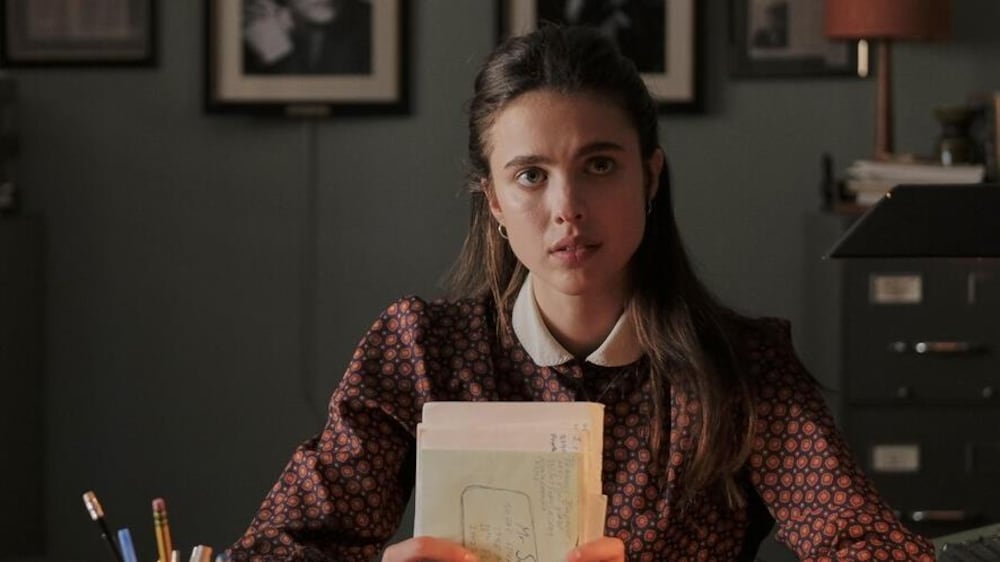 Micro_scope Une jeune femme (Margaret Qualley) assise à un bureau, des lettres entre les mains.