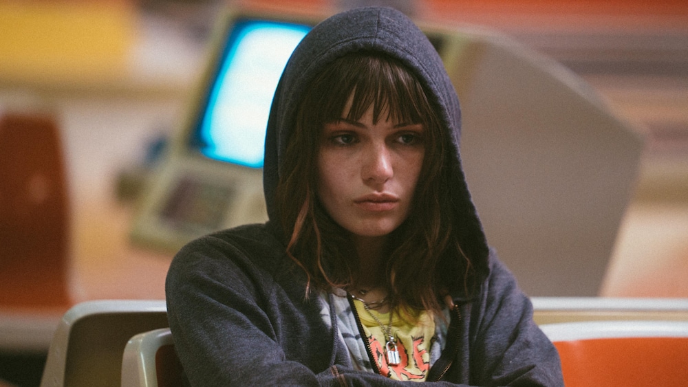 K-Films Amérique Une jeune femme (Kelly Depeault) l'air renfrogné, une capuche sur la tête.
