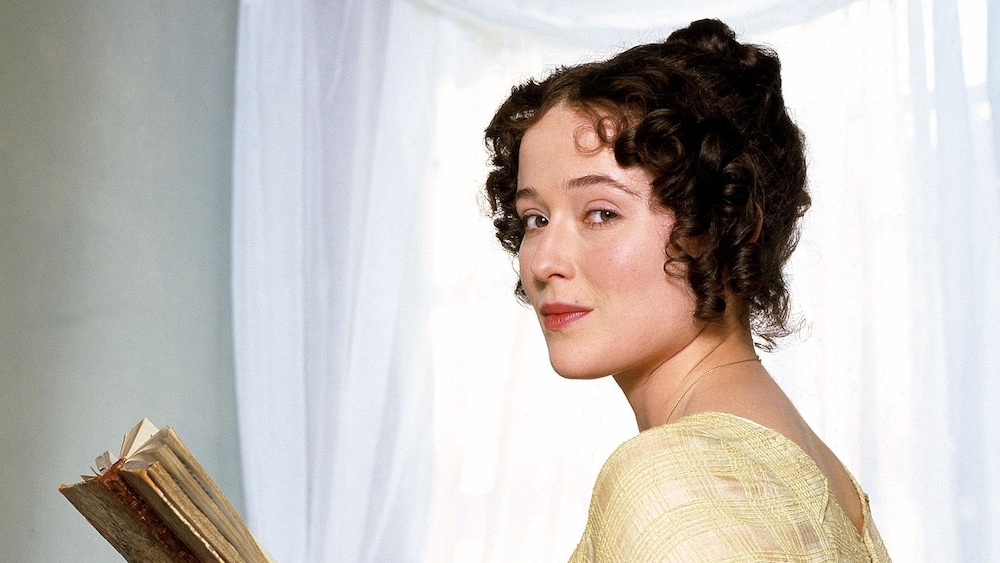 Elizabeth Bennet est assise, un livre dans la main et le regard porté vers la caméra. 