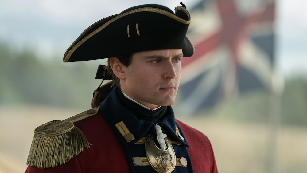 L'acteur en costume d'époque avec un drapeau britannique en arrière-plan.