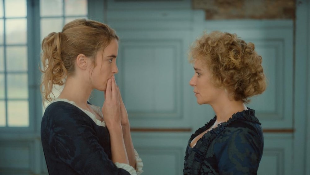 Une jeune femme, les mains sur la bouche, face à une femme.