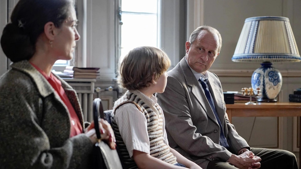 Axia Films Un homme, un enfant et une femme assis côte à côte sur un canapé.