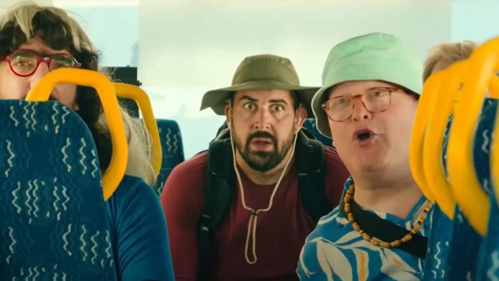 AZ Films Un homme assis au fond d'un bus, derrière des jeunes.