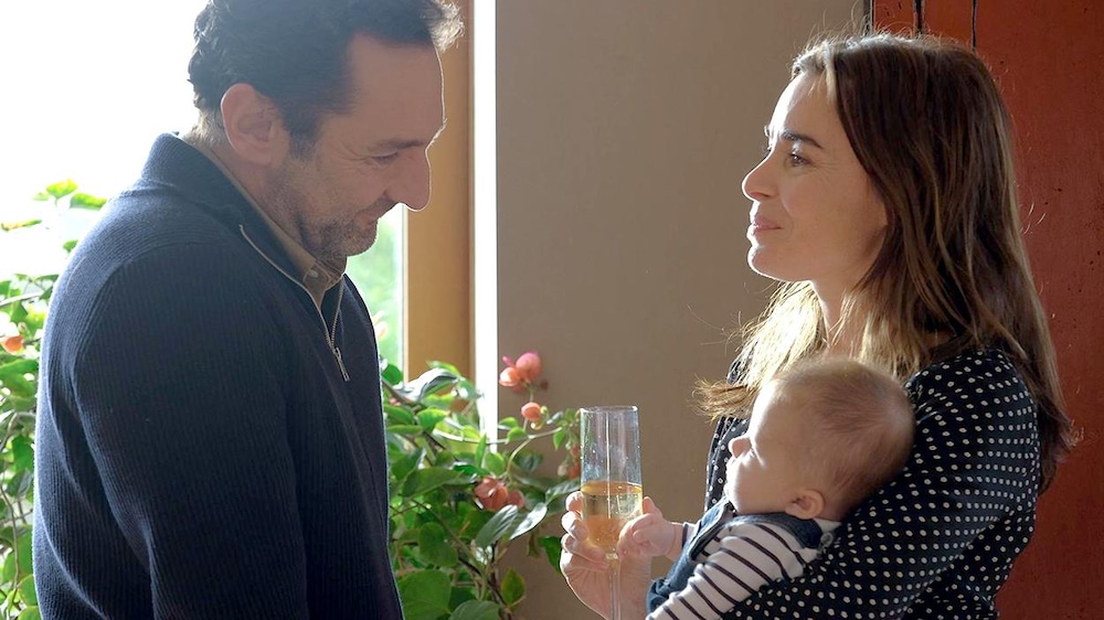 Trésor Films Un homme regarde une femme qui tient un bébé dans ses bras.