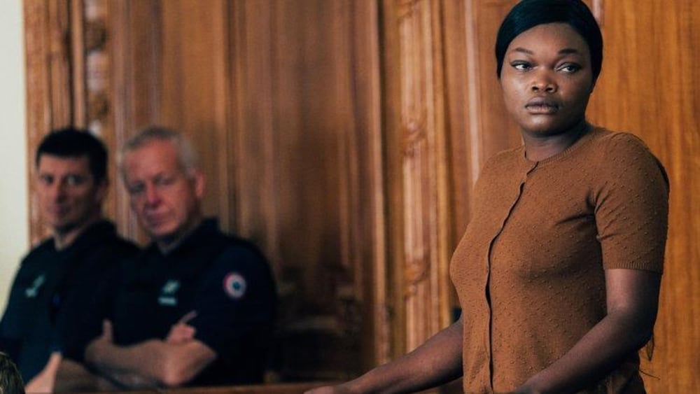 Une femme se tient debout, derrière le banc des accusés d'un tribunal.