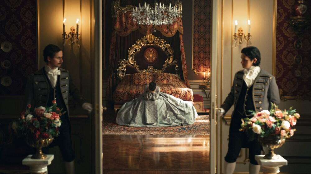 L'impératrice Sissi assise sur son lit, le visage caché dans ses mains.