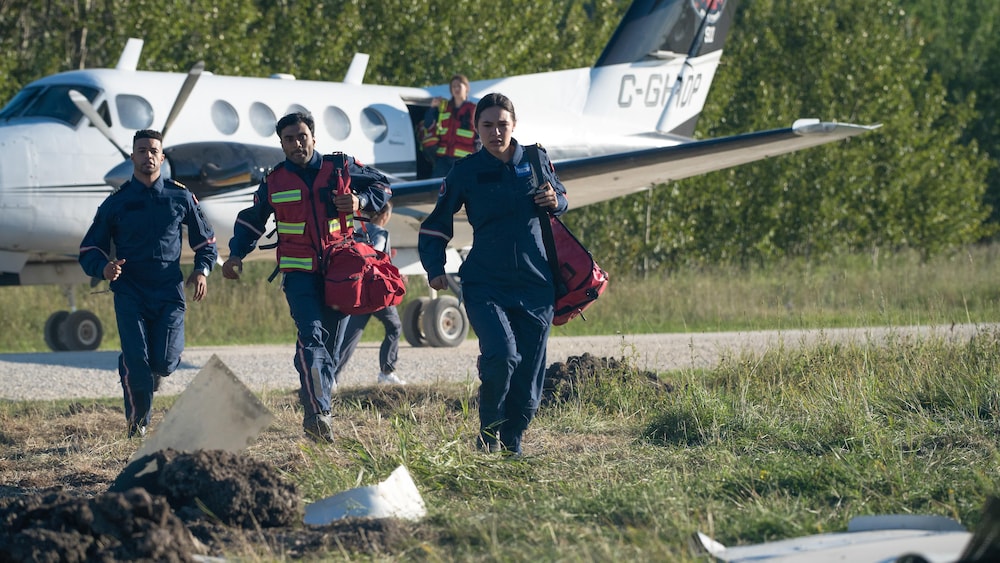 cbs tv studios / Pief Weyman Une équipe de sauvetage médical descend d'un avion qui a atterri au milieu d'un champ.