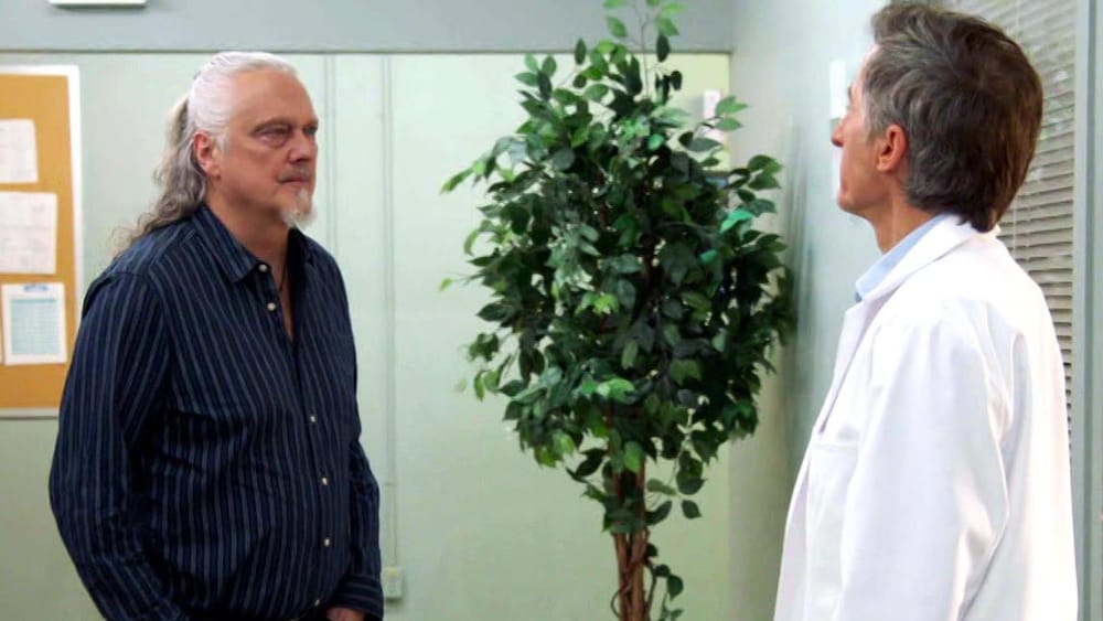 Pascal et Laurent sont face à face dans un corridor de l'hôpital.