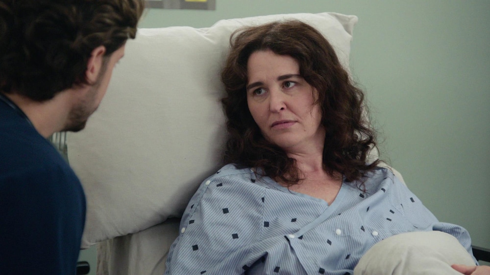 Céline est couchée sur son lit d'hôpital et elle regard une personne à côté d'elle.