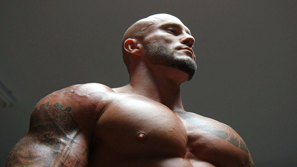 Un culturiste, torse nu, en contre plongée.