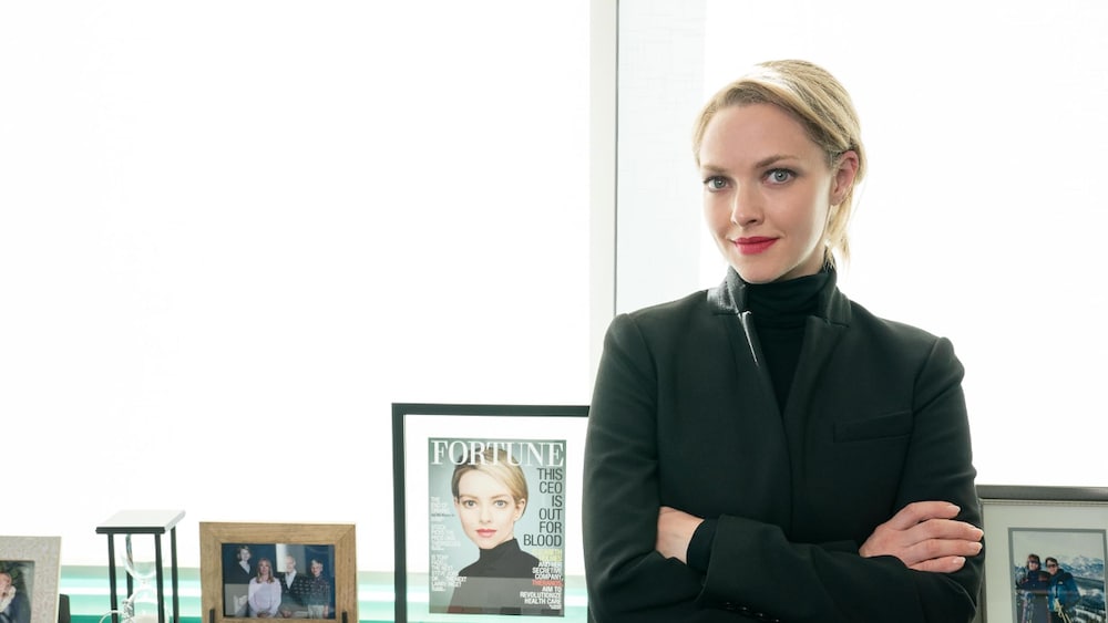Beth Dubber/ Hulu La femme croise les bras et elle est debout devant une étagère avec des photos.