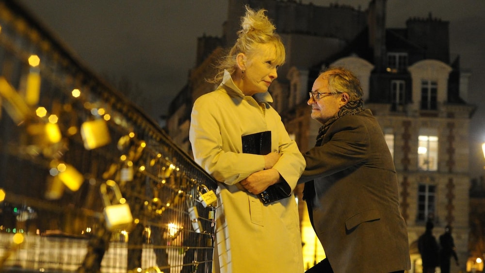 La nuit, un couple de personnes âgées sur un pont, à Paris.