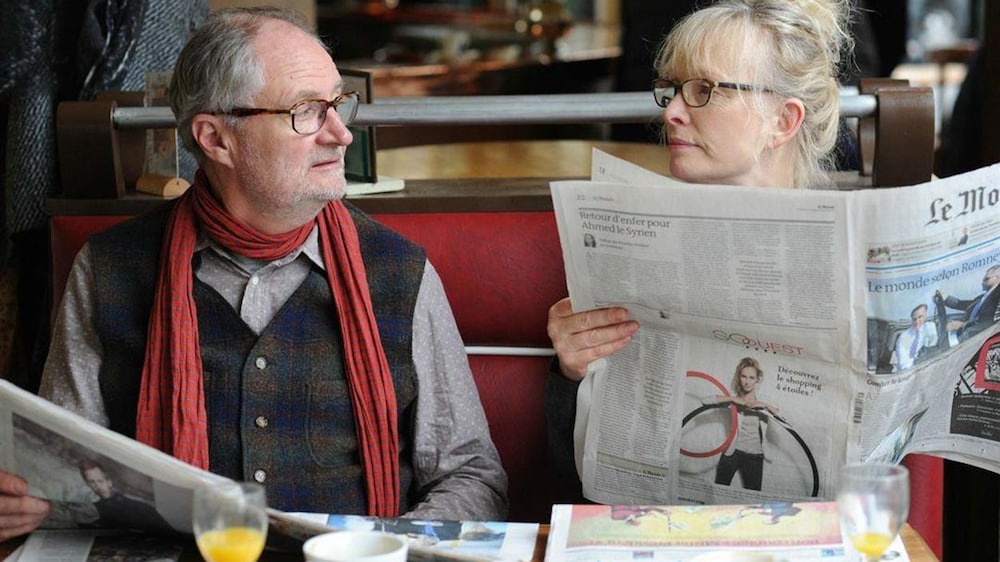 Un homme et une femme assis côte à côte dans un café, des journaux dans les mains