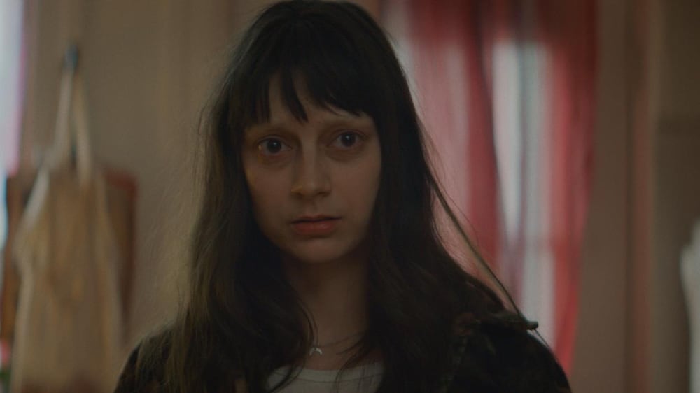 Une jeune femme, les cheveux mal coiffés et les yeux cernés.