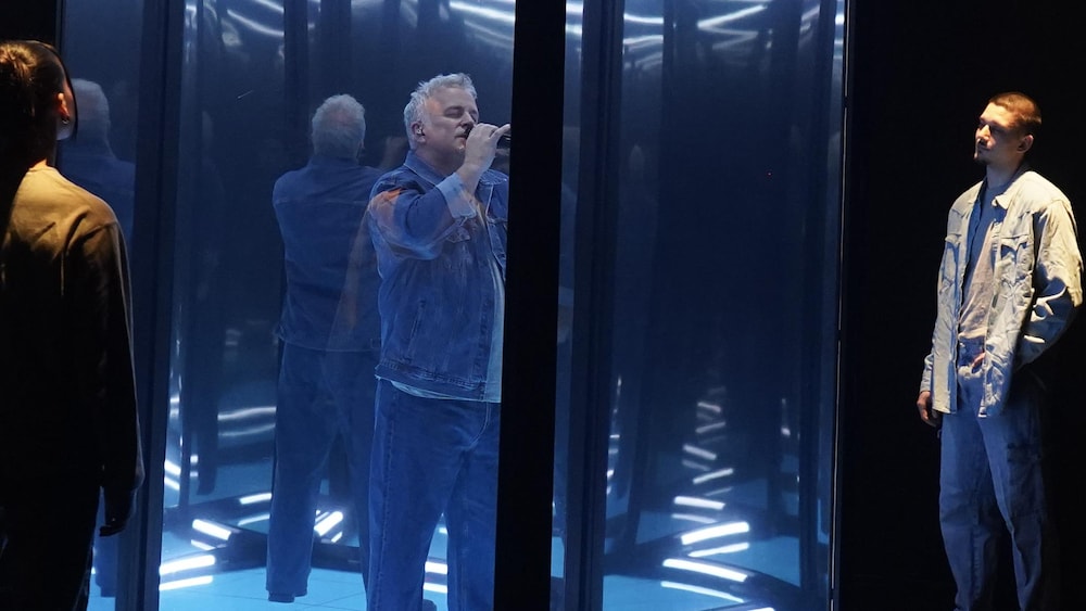 Marc Déry chante sur la scène dans une cage de verre.