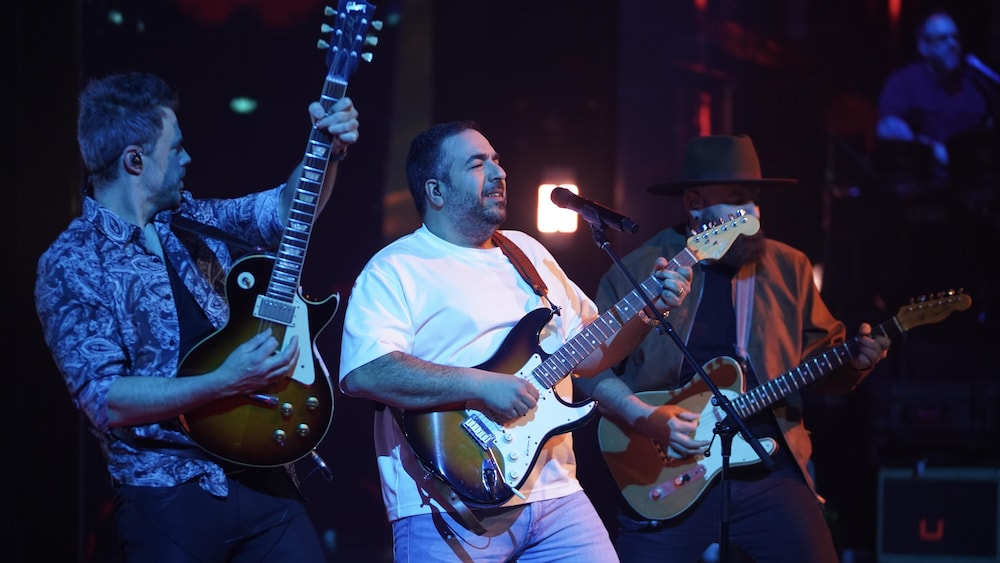 Neev joue de la guitare sur le plateau.