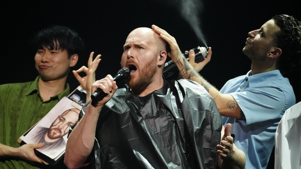 Constant Bernard, chante avec passion, entourée d'une équipe de coiffeurs maquilleurs.