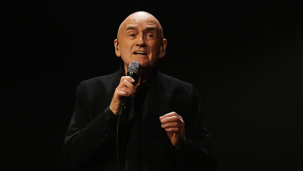 Joël Denis, joue au DJ devant une foule dansante.  