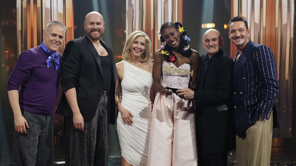 Les artistes sont sur le plateau l'animatrice crie le bras en l'air.