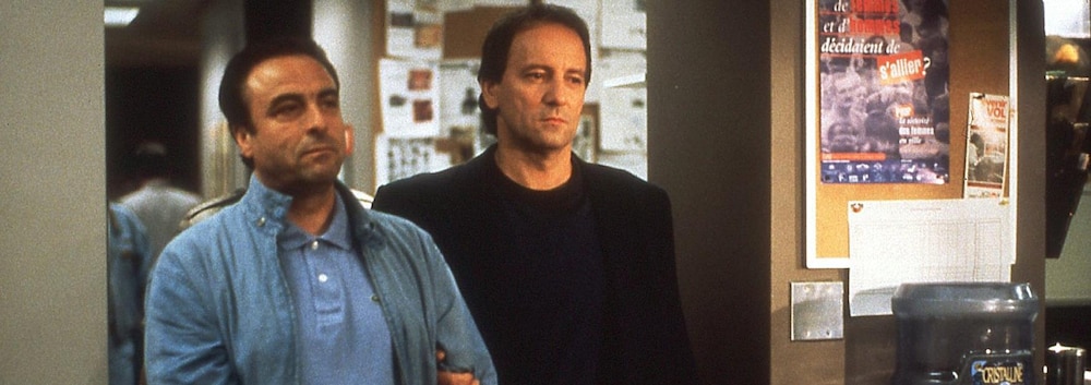 Giuseppe Scarfo (Dino Tavarone), menotté, est amené au poste par Pierre Gauthier (Michel Côté).