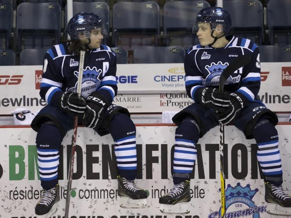 Christal Films Deux hockeyeurs (dont Antoine-Olivier Pilon) en tenue, assis sur le côté de la patinoire.