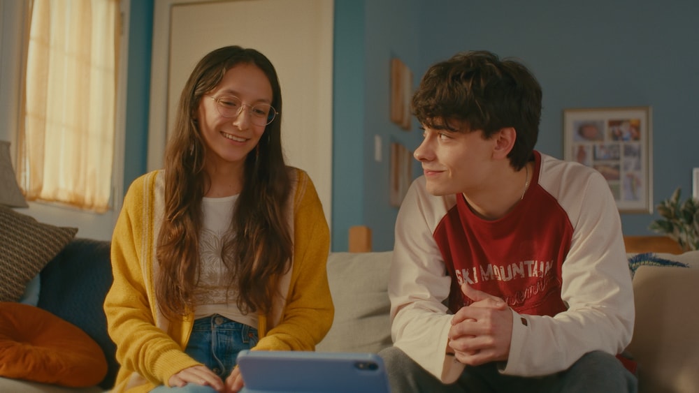 Les deux ados sourient en regardant une vidéo. 