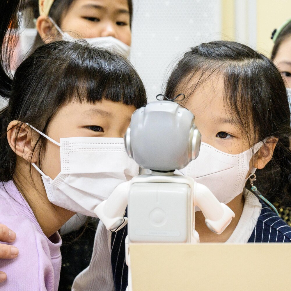 Cinq jeunes enfants sud-koréens interagissent avec un robot "Alpha Mini"
