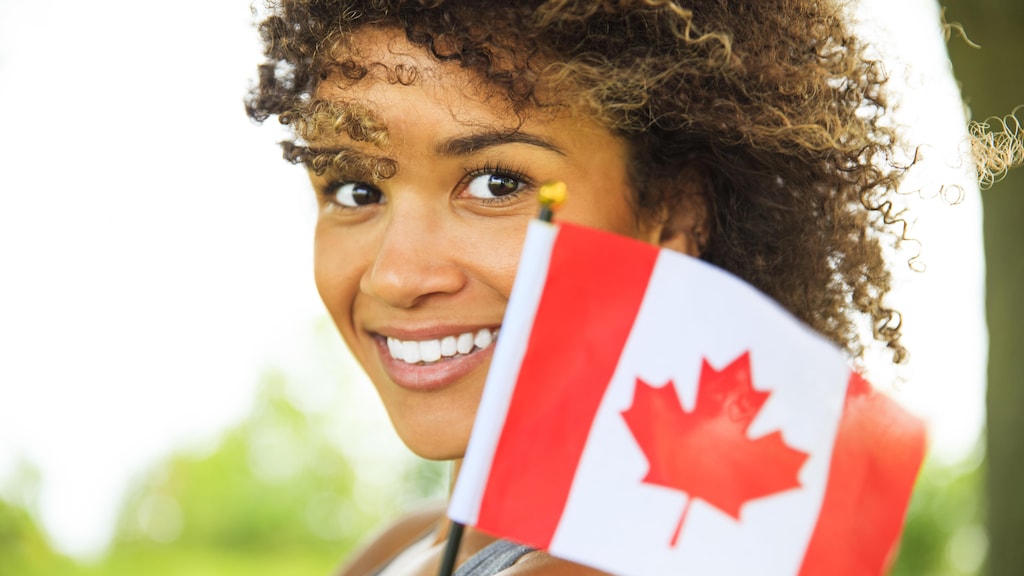 Happy young woman with Canadian flag outdoor portrait