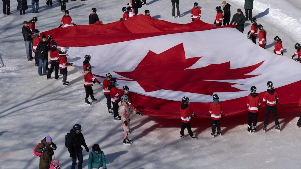 Members of the public skating on the Rideau Canal pass youth holding a giant Canadian flag as part of launch celebrations for the 60th Anniversary of the National Flag of Canada Day, Friday, Feb. 14, 2025 in Ottawa.  THE CANADIAN PRESS/Adrian Wyld