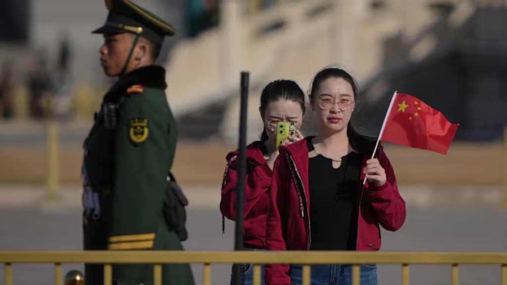一名女性手持中国国旗,在站岗的中国武警官兵旁合影留念。