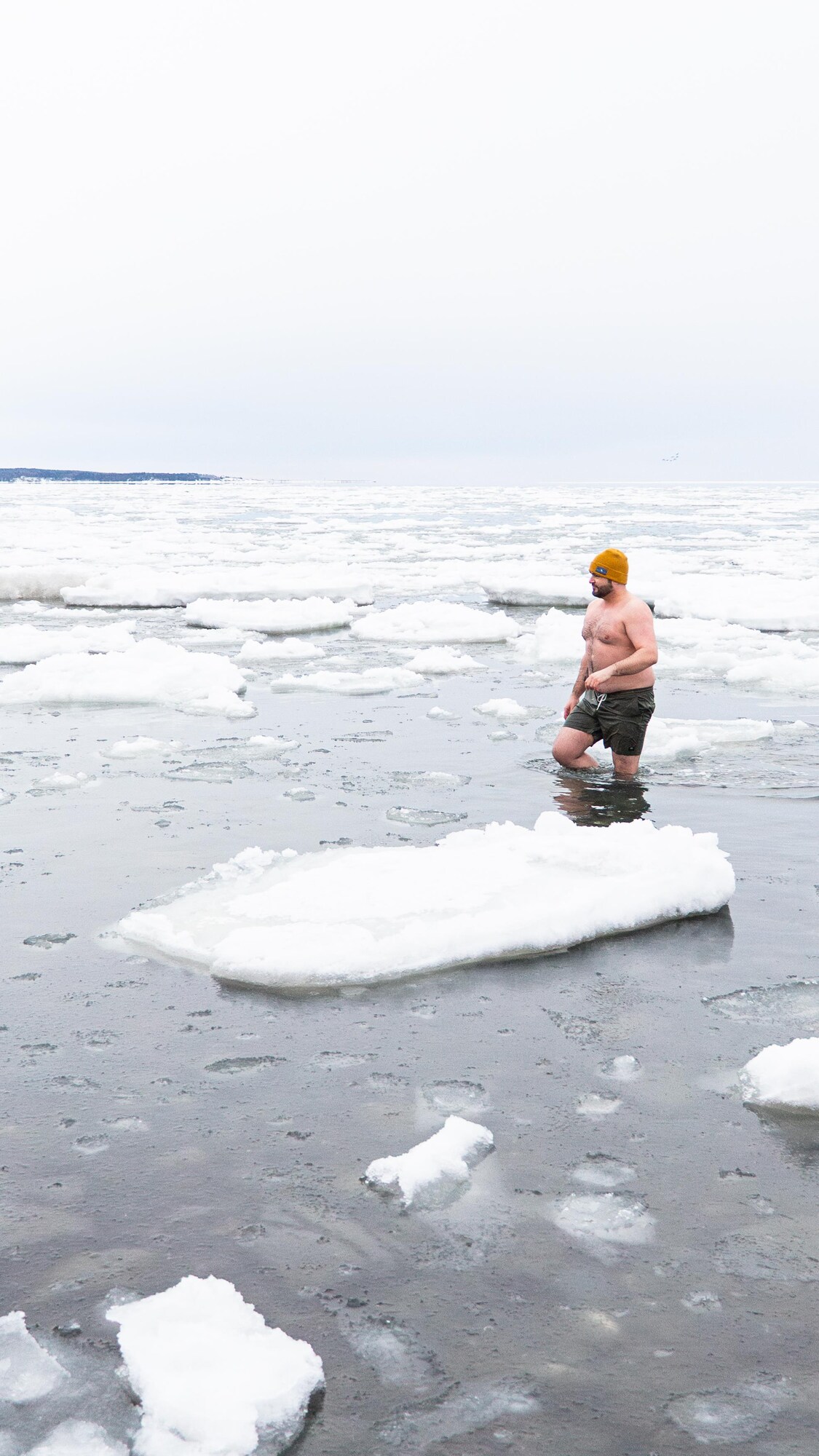 Un homme marche dans l’eau entouré de morceaux de glace.