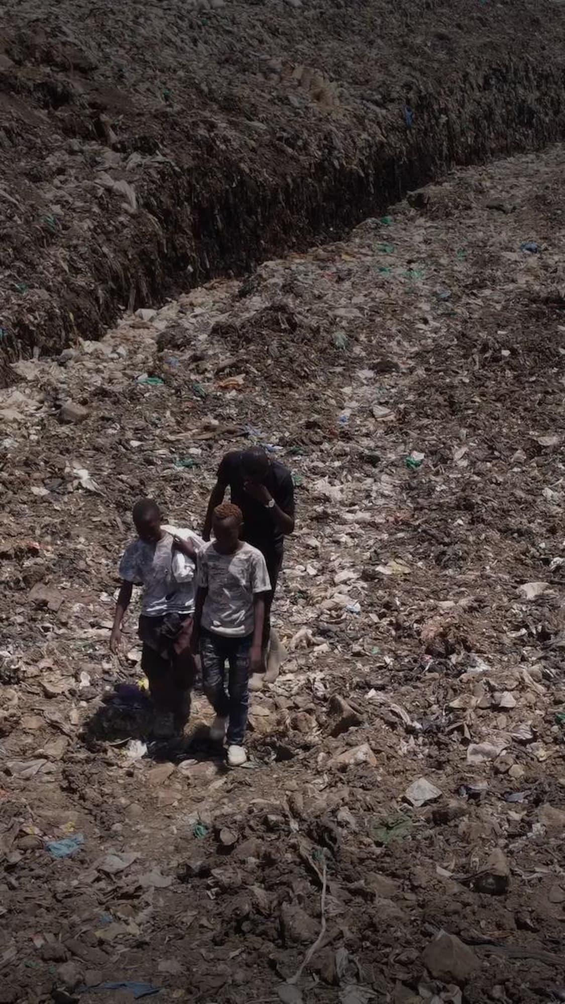 Des enfants devant un sac de déchets.