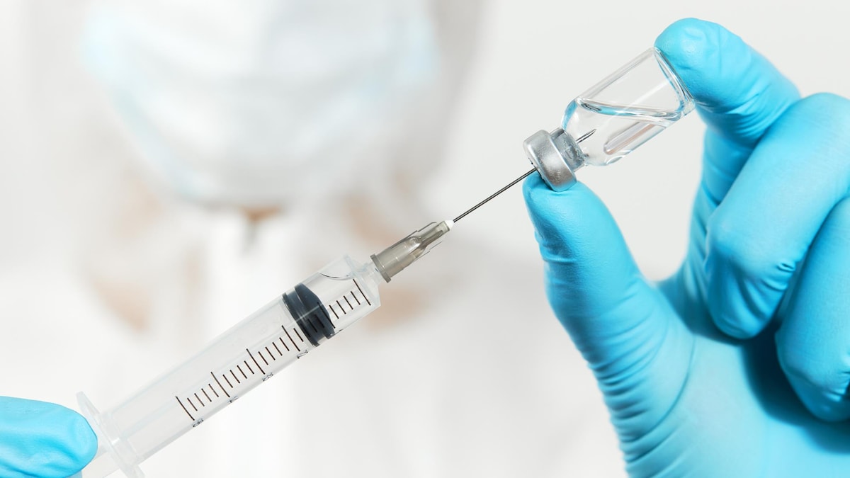 Un médecin tient un flacon de vaccin et une seringue pour l'injection.