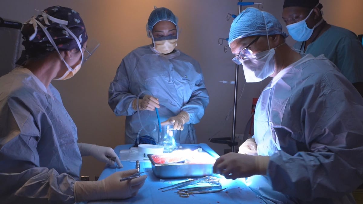 Des médecins réunis autour d'une table dans une salle d'opération, en train de choisir des instruments pour pratiquer un acte.