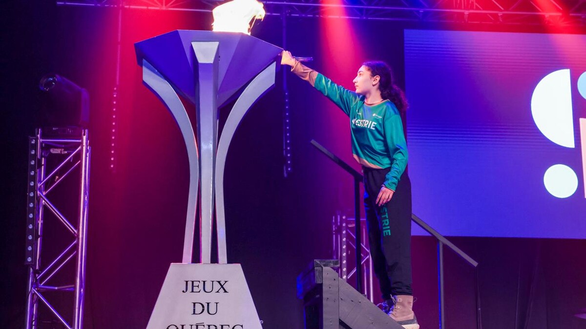 Une jeune fille allume la flamme des Jeux du Québec.
