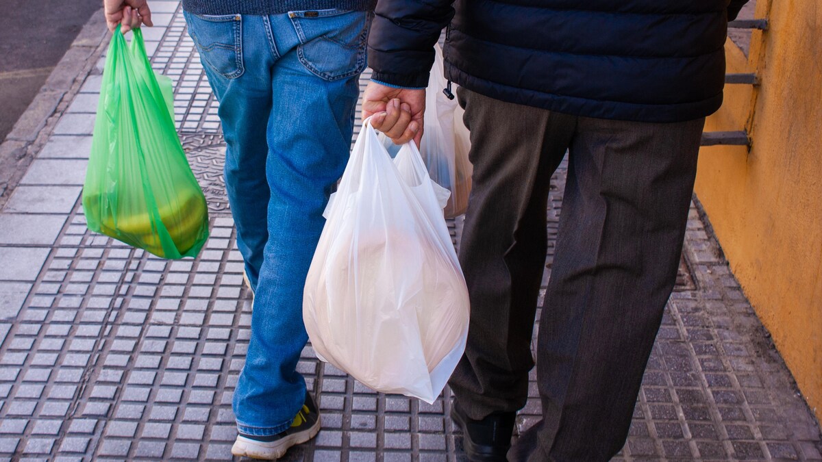 Deux personnes tenant des sacs plastiques.