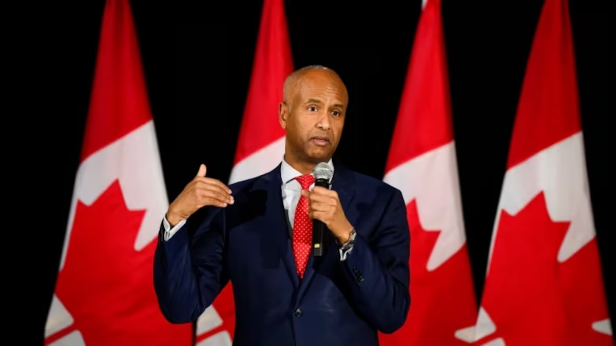 Ahmed Hussen s'exprime au micro devant des drapeaux canadiens.