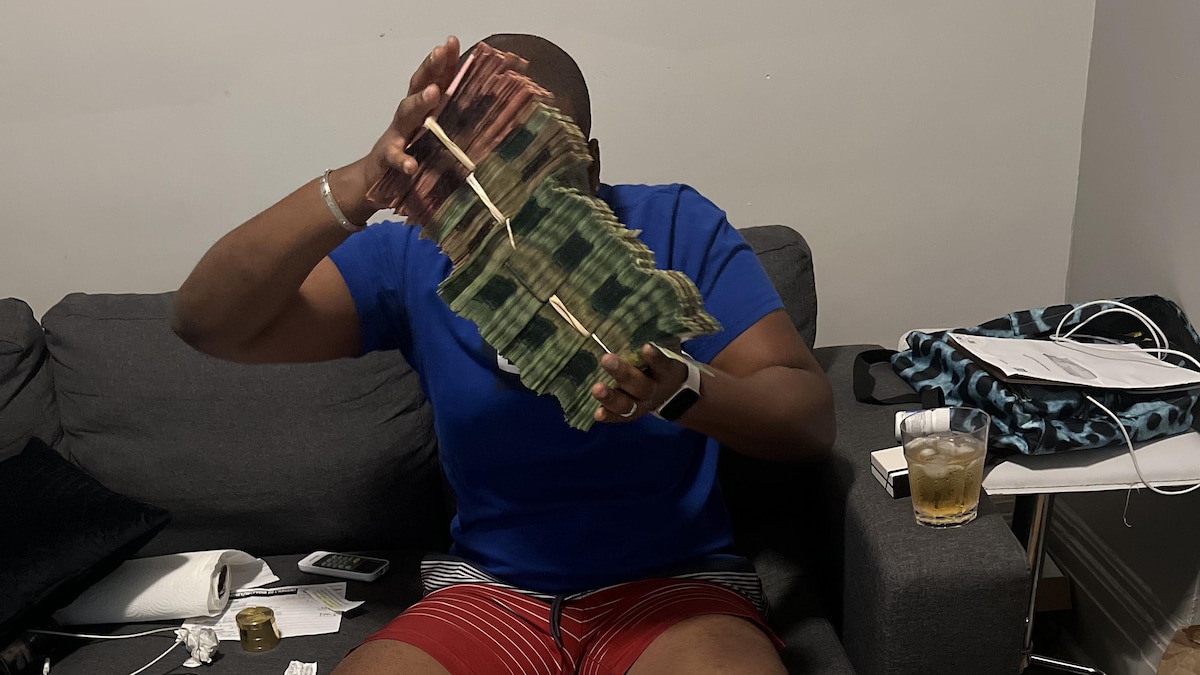 Un fraudeur montre des billets de banque.