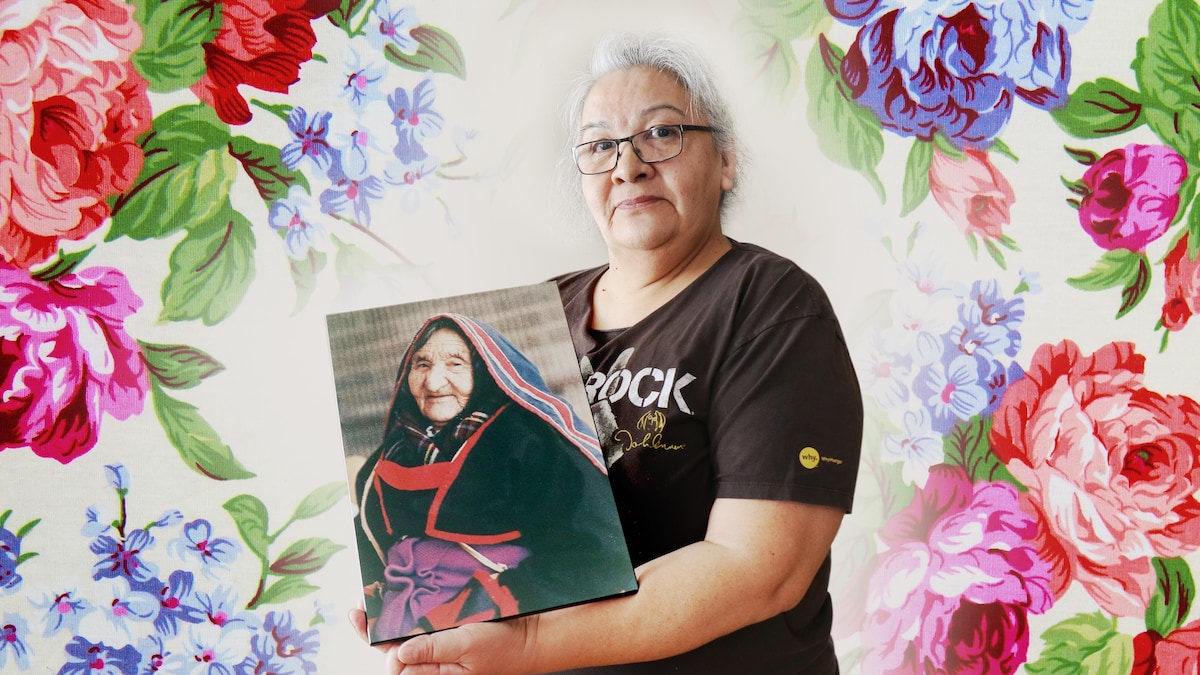Une femme présente le portrait d'une autre femme, sa grand-mère.