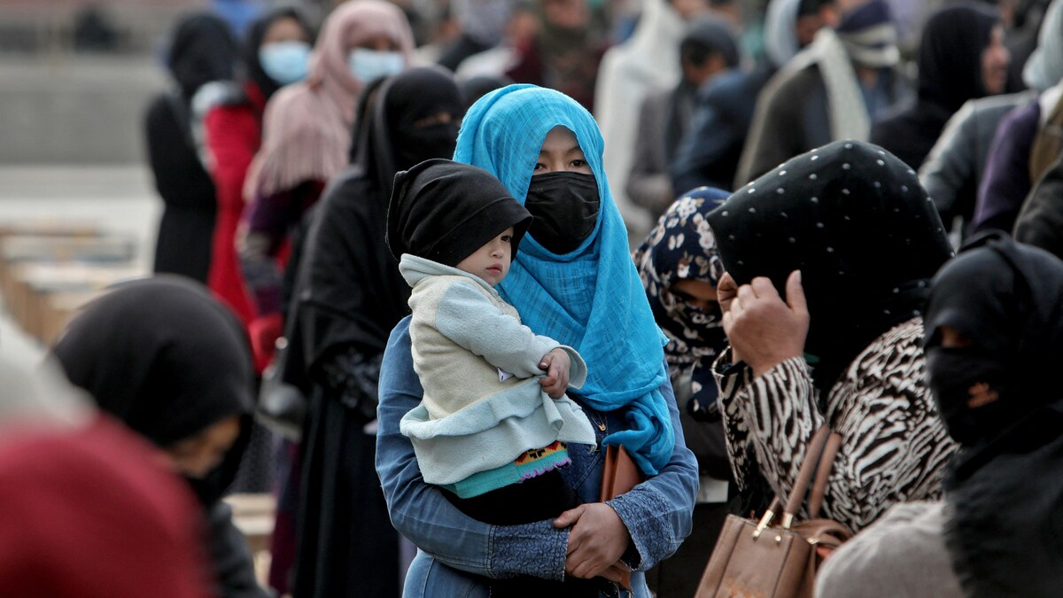 Une Afghane voilée tient son enfant dans ses bras au milieu d'une foule.