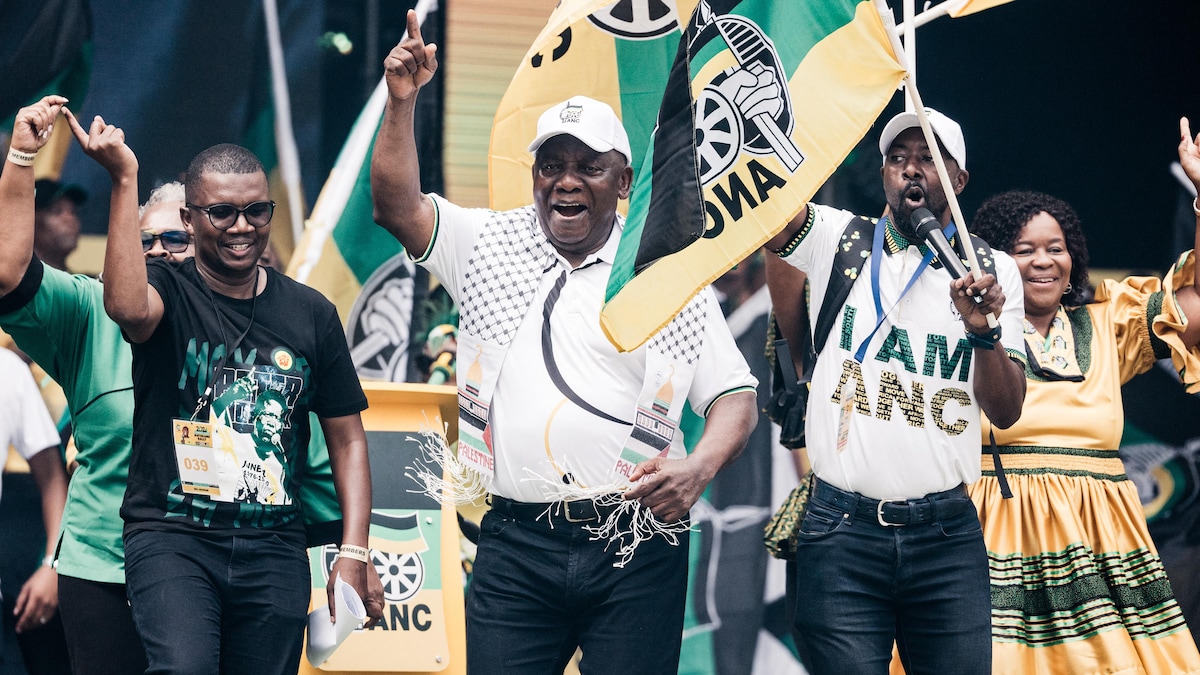 Cyril Ramaphosa danse à côté de personnes tenant des drapeaux aux couleurs de l'ANC.