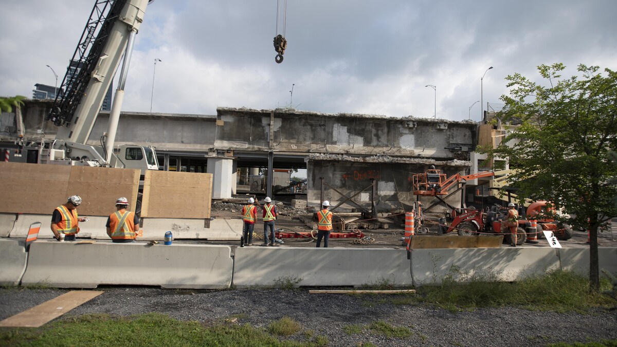 Des ouvriers près de vieilles poutres de l'ancien pont Champlain.