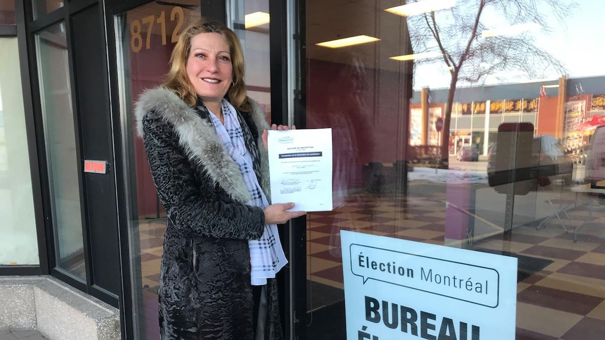 La candidate du parti Ensemble Montréal, Angela Gentile, pose tout sourire avec sa feuille de candidature devant le bureau d'Élection Montréal.