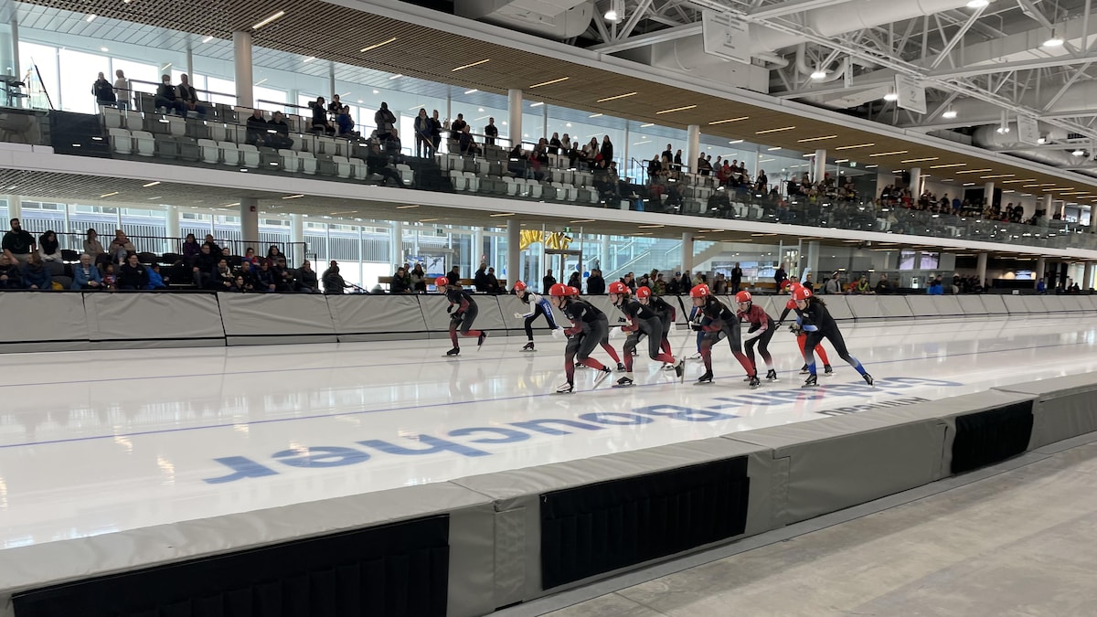 Des patineurs sur la glace s'élancent devant des spectateurs.
