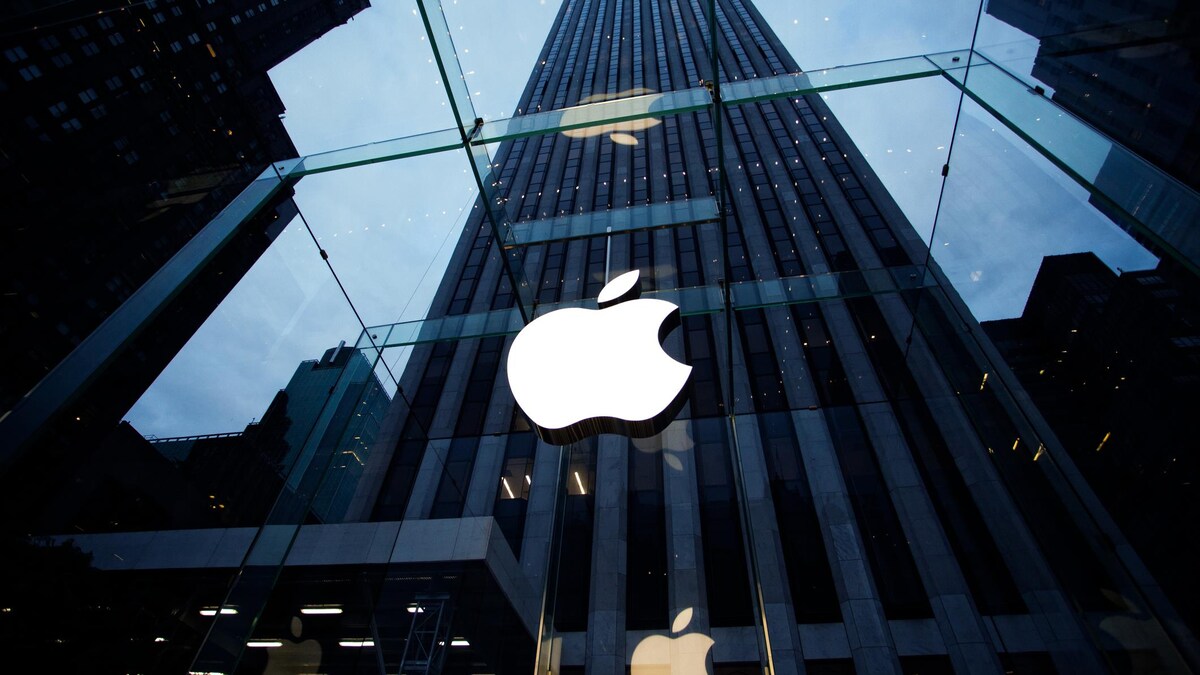 La devanture de la boutique d'Apple située au centre-ville de New York. La pomme illuminée orne un mur de verre, au travers duquel on aperçoit un gratte-ciel haut de dizaines d'étages.