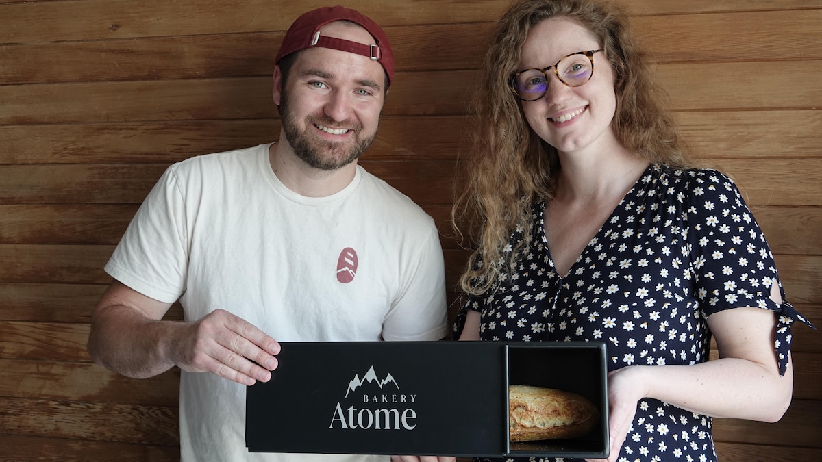 Alice Couderc et Lucas Navilloz tiennent une boîte de cuisson portant le logo d'Atome Bakery et contenant une baguette.
