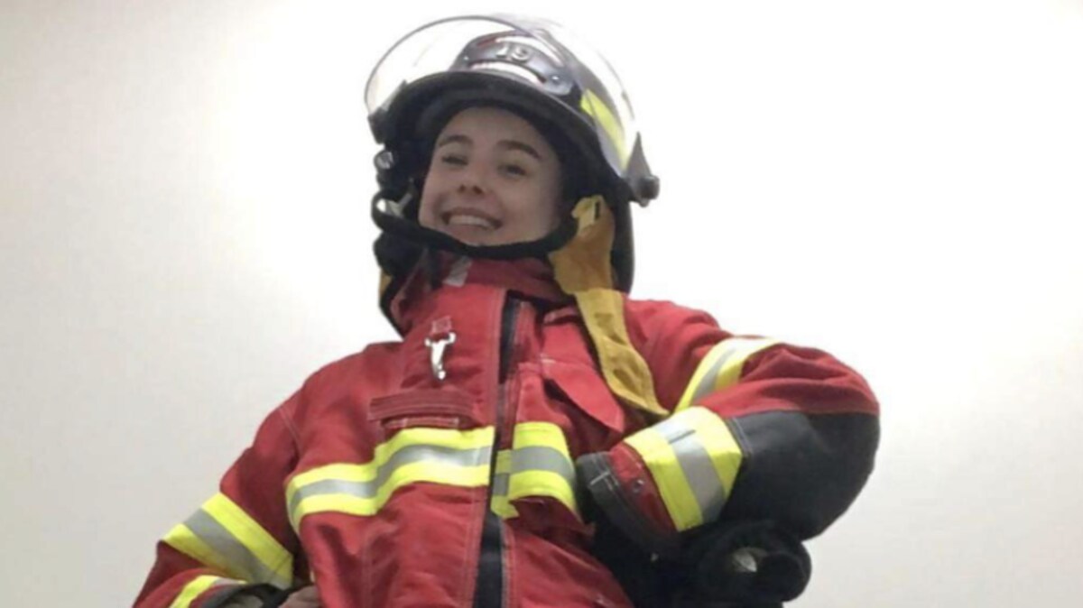 Une jeune fille souriante, portant son habit de pompière.